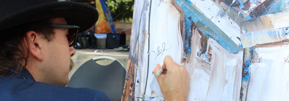 Band Member signing painting of piano